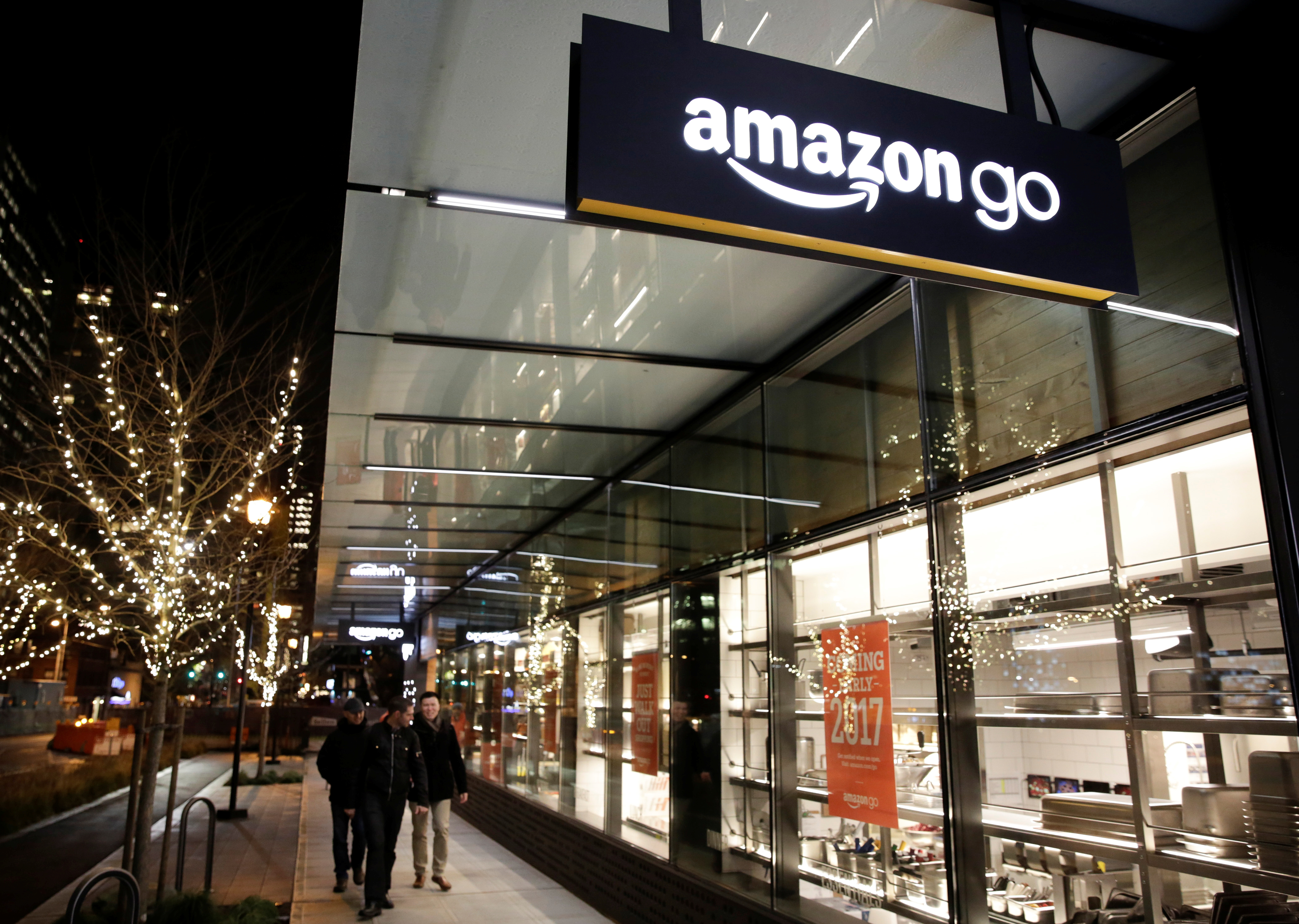 People walk by the Amazon Go brick-and-mortar grocery store without lines or checkout counters, in Seattle Washington, U.S. December 5, 2016. REUTERS/Jason Redmond - RTSUU23